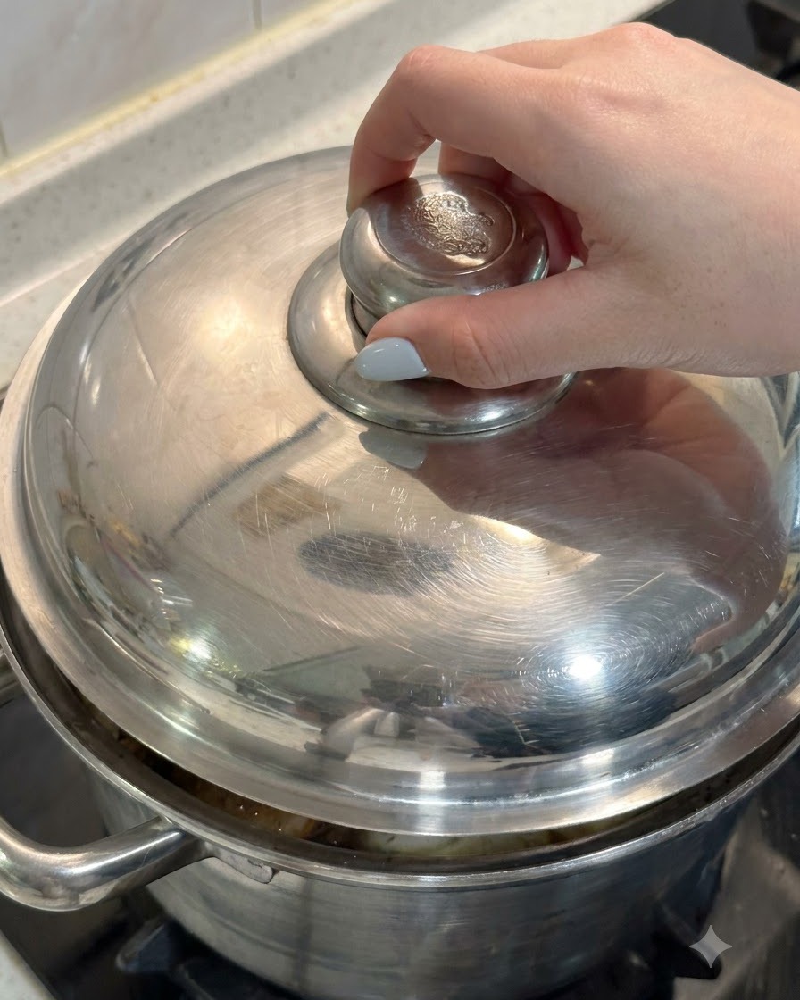 A hand placing the metal lid onto a pot filled with chicken and soup ingredients.