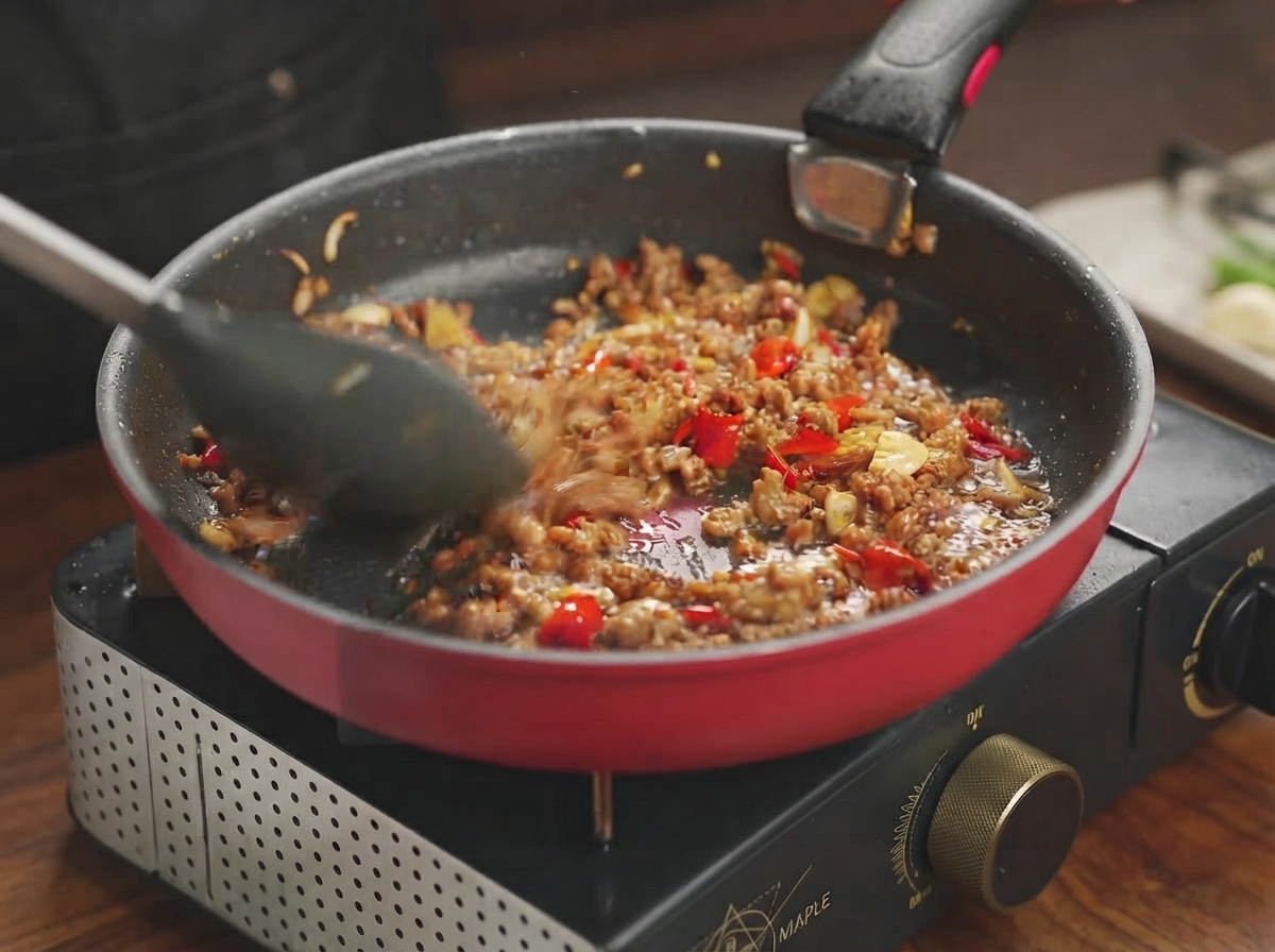 Pork mixture simmering and absorbing the savory sauce in a frying pan.