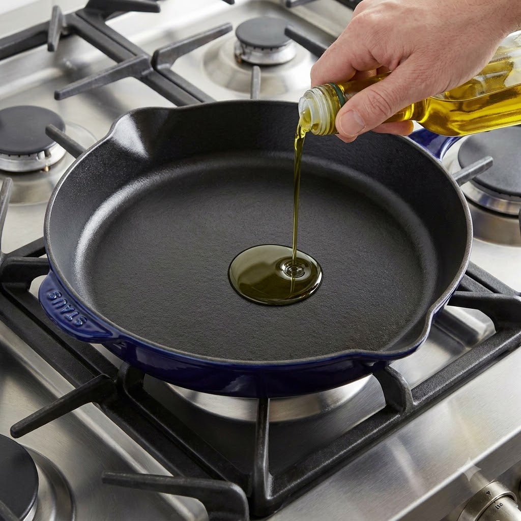 Olive oil being poured into a preheated cast iron skillet.