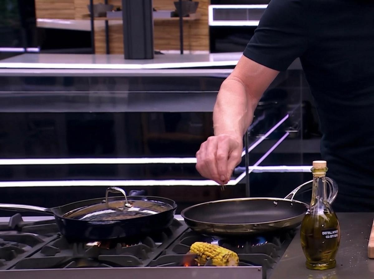 A seasoned corn cob being roasted and charred directly over an open gas flame on the stove.