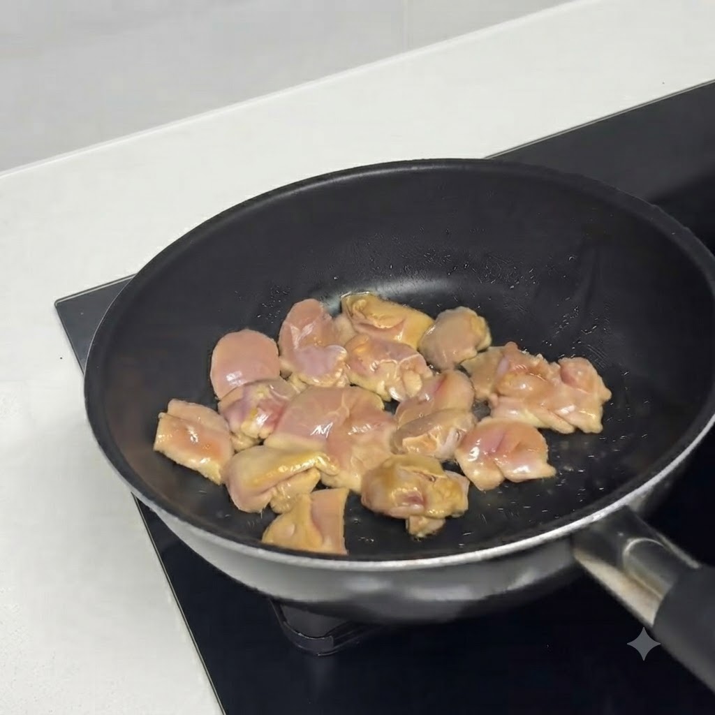 Marinated chicken pieces sizzling in a hot oiled pan.