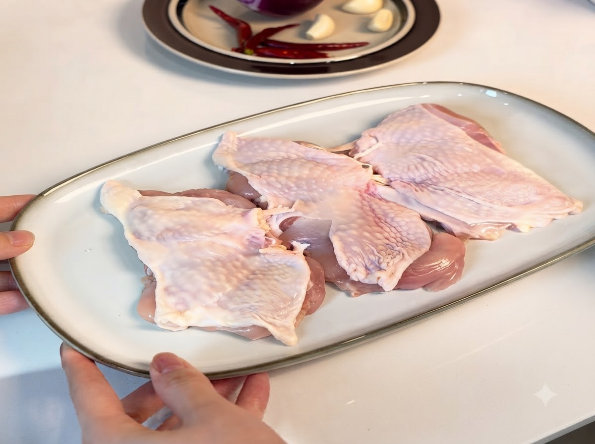 Boneless chicken thighs arranged on a white serving plate, coated with seasonings.