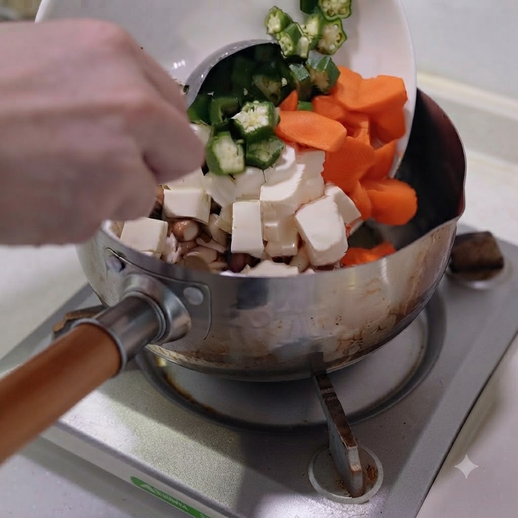 Chopped vegetables and tofu being poured from a white plate into a stainless steel pot.