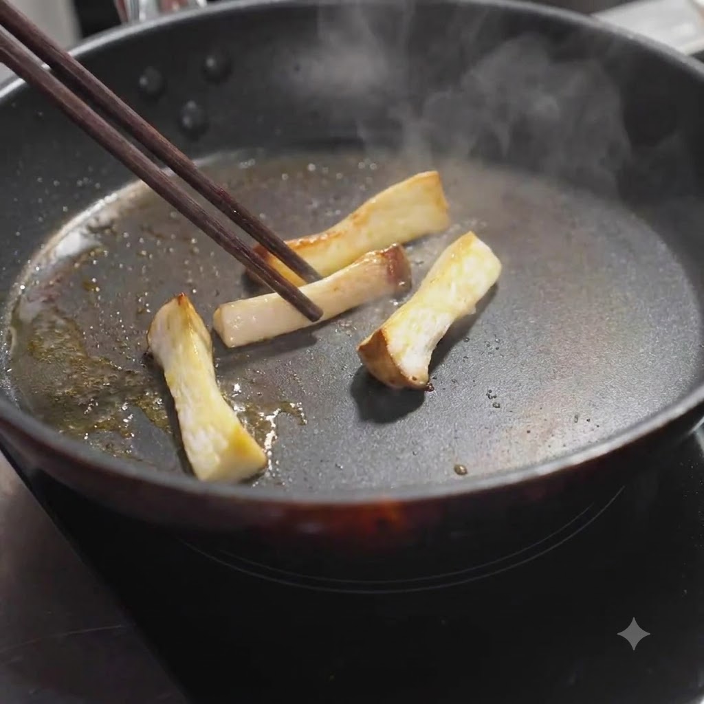 Slices of king oyster mushrooms being turned in the pan with chopsticks until golden browncite: 1.