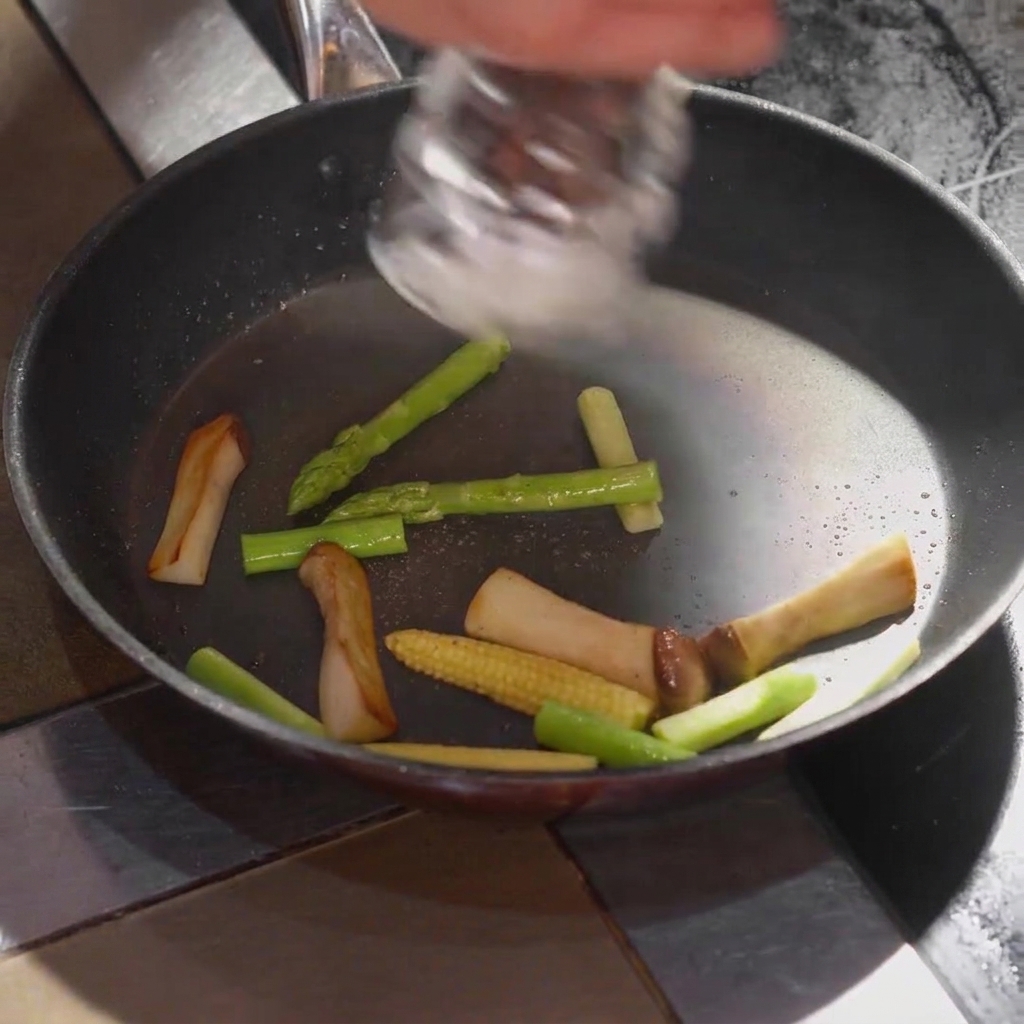 Salt being seasoned onto the vegetables inside the cooking pan.