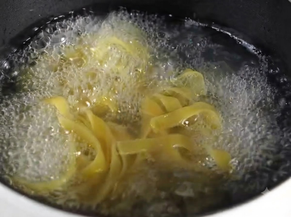 A close-up view of cooked fettuccine pasta piled neatly on a round gray plate.