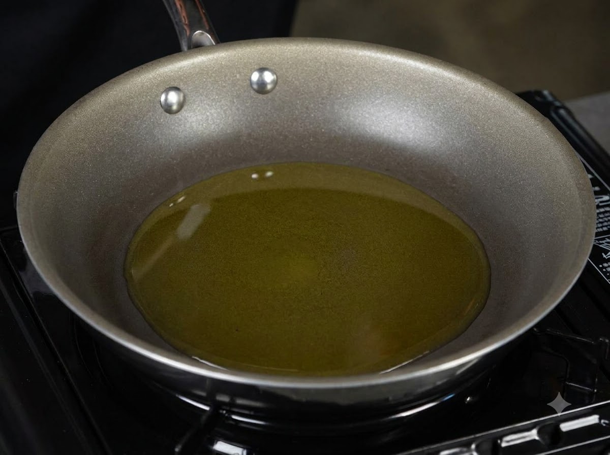 A frying pan filled with heated olive oil resting on a stove burner.