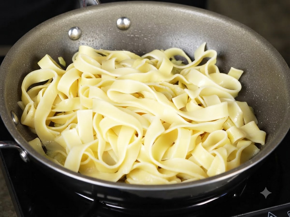 A ladle scooping and pouring starchy pasta water over the noodles inside the cooking pan.