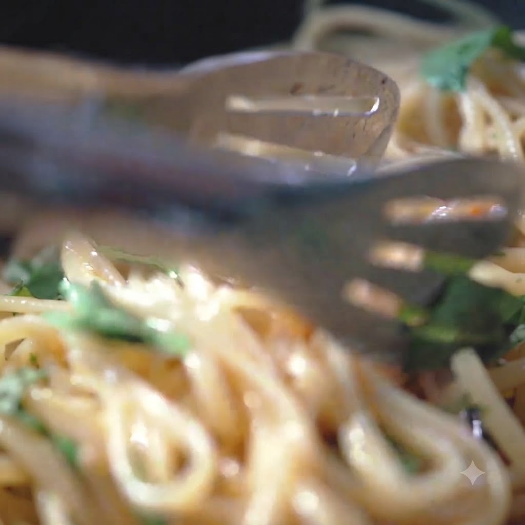 Black pepper and sea salt being sprinkled over pasta noodles in a hot pan.