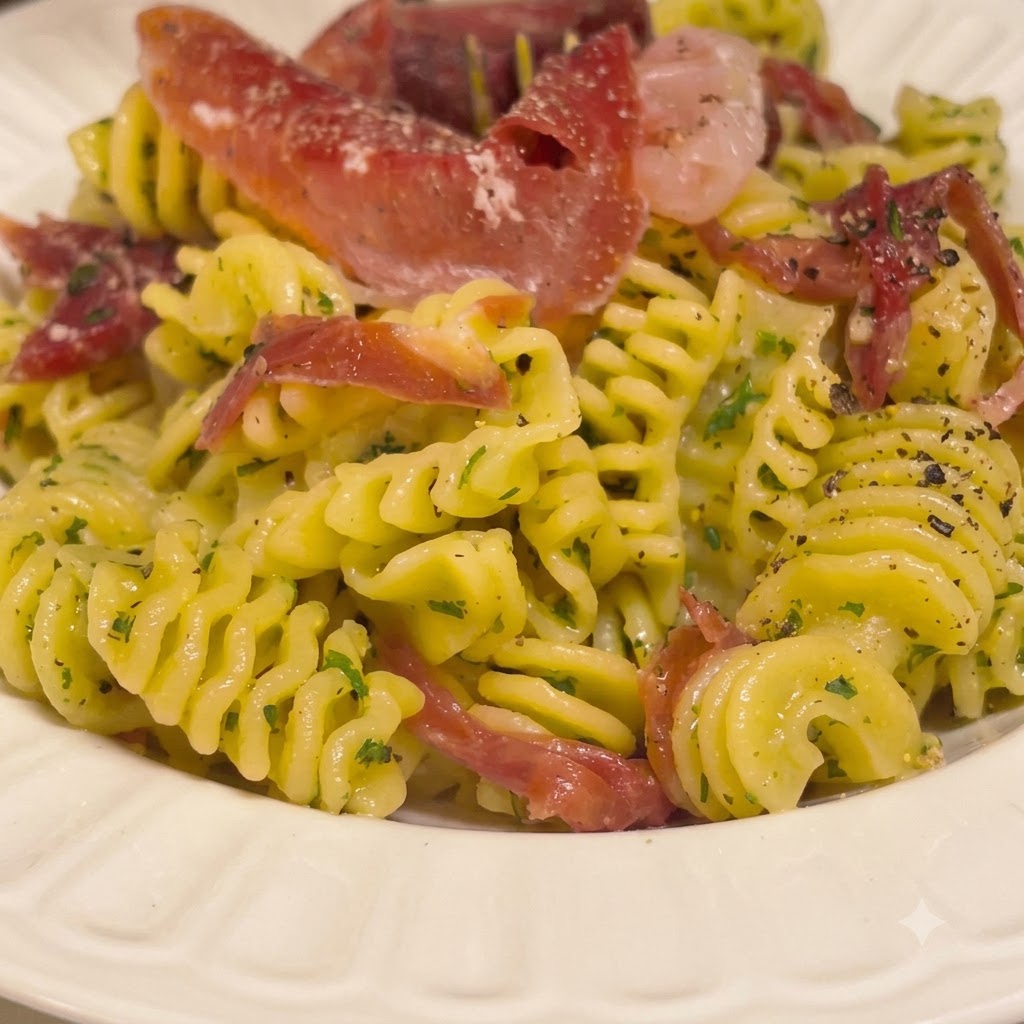 Cooked spiral pasta being tossed in a white bowl with a rich buttery sauce using kitchen tongs.