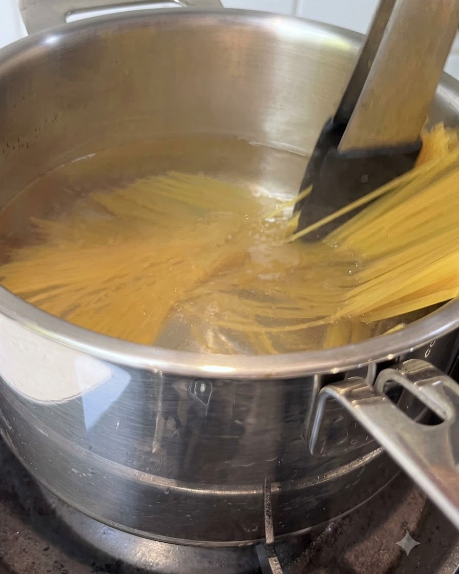 Spaghetti being stirred with tongs in a pot of boiling water.