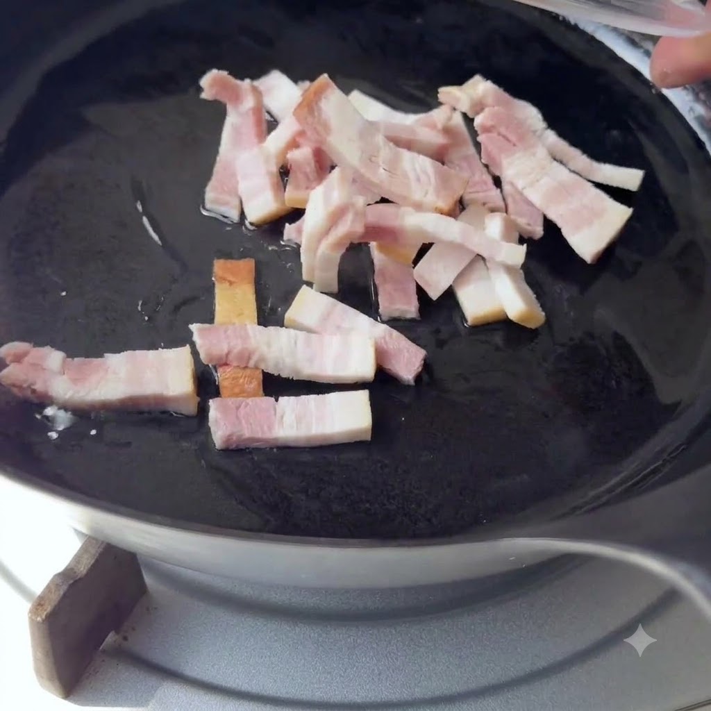 Small strips of bacon being dropped into a black skillet with hot oil.