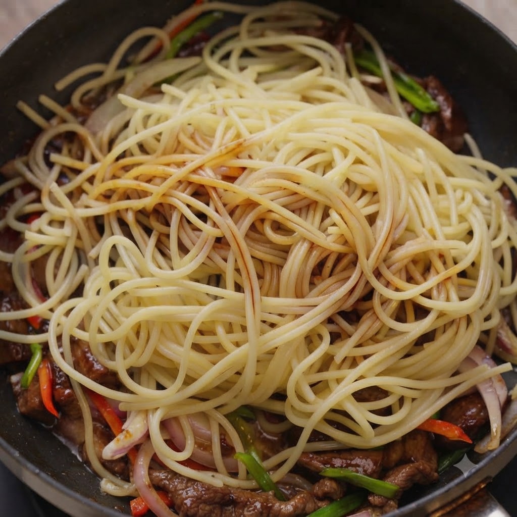 Sauces being drizzled over spaghetti noodles and beef inside a cooking pan.