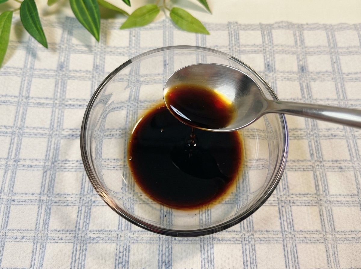Soy sauce and other seasonings being stirred inside a glass bowl with water.