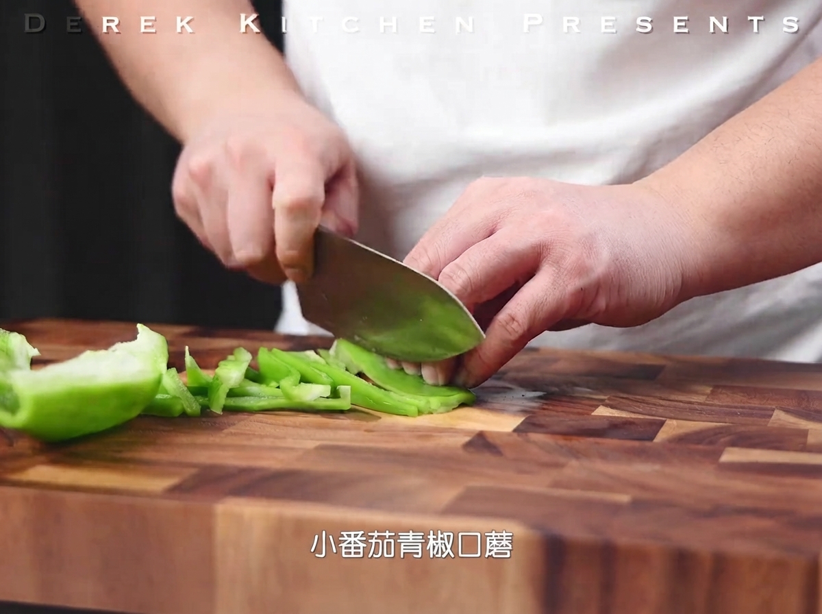 Green bell peppers being sliced into thin strips on a wooden cutting board.