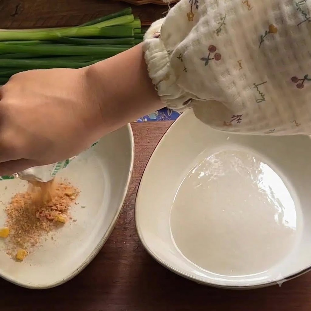 A hand pouring dry seasoning powder from a packet into a white ceramic bowl.