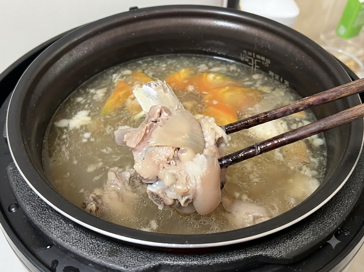 Chopsticks lifting a tender piece of meat from the cooked broth.