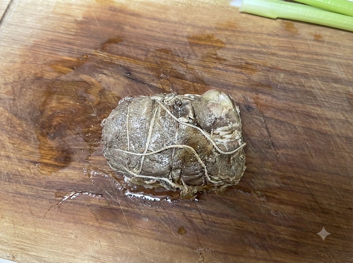Tied rolled pork chashu resting on a wooden cutting board before being sliced.