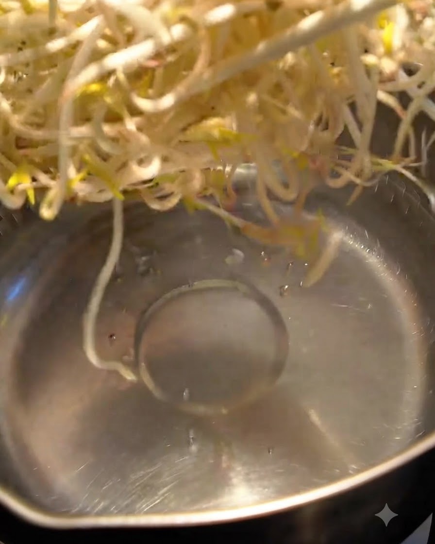 Mung bean sprouts being blanched in boiling water in a pot.