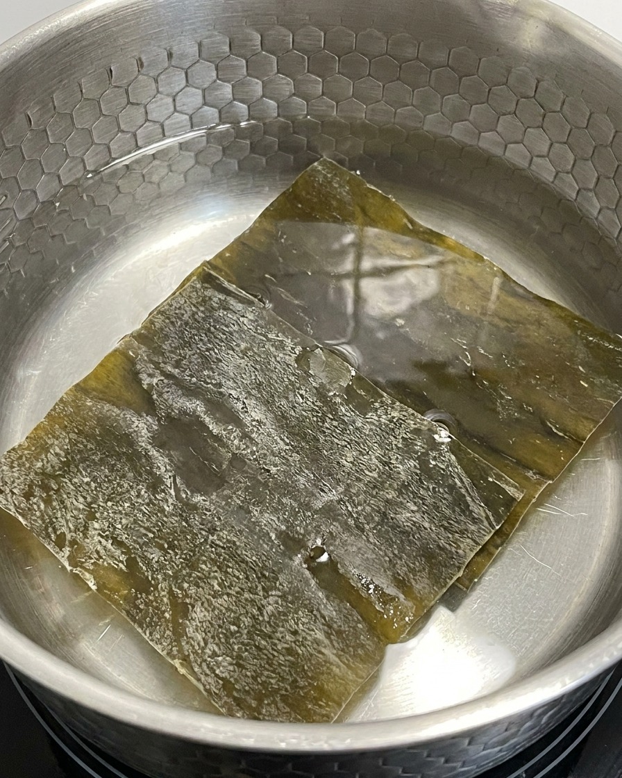Dried kelp pieces soaking in a pot of water over low heat.