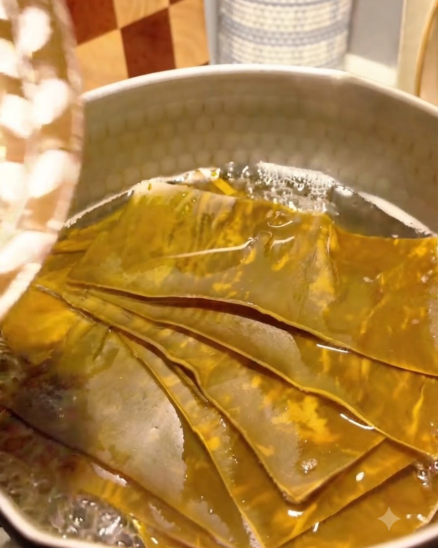 Bonito flakes added to the simmering kelp broth in a pot.