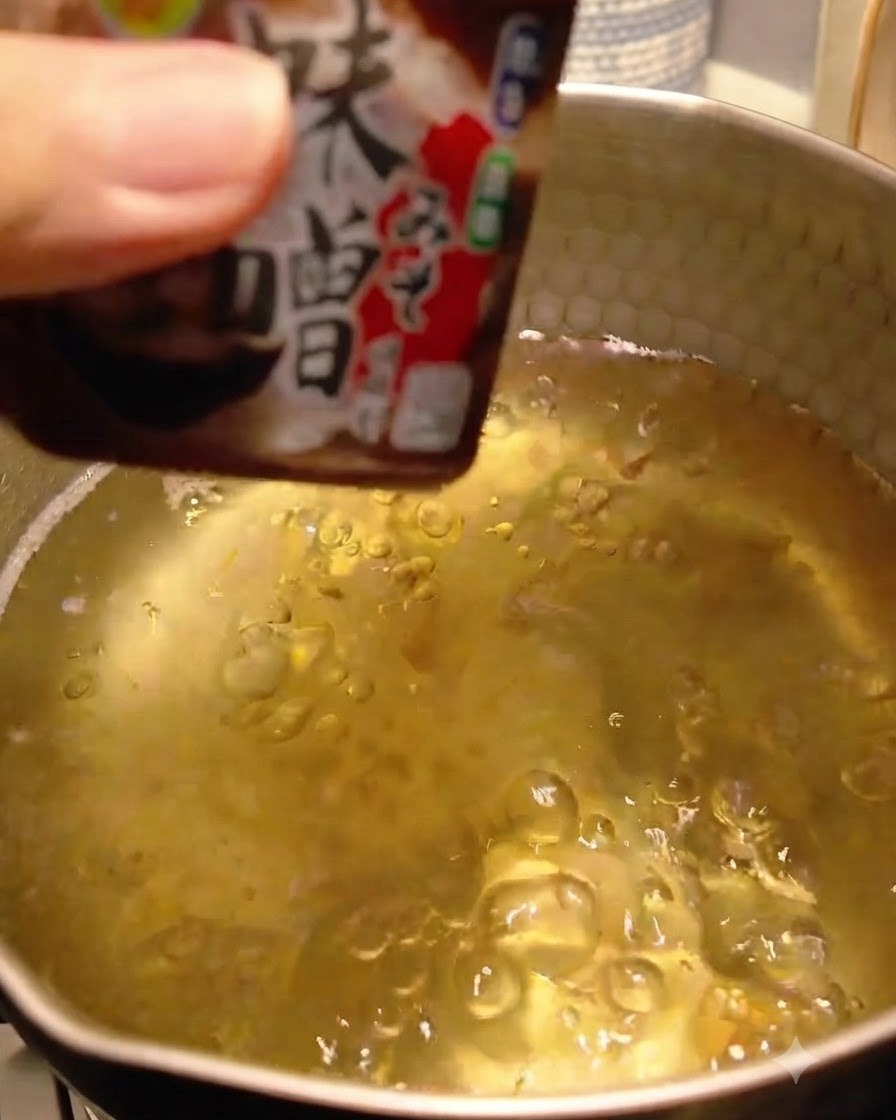 Miso paste being added and dissolved into the dashi broth.
