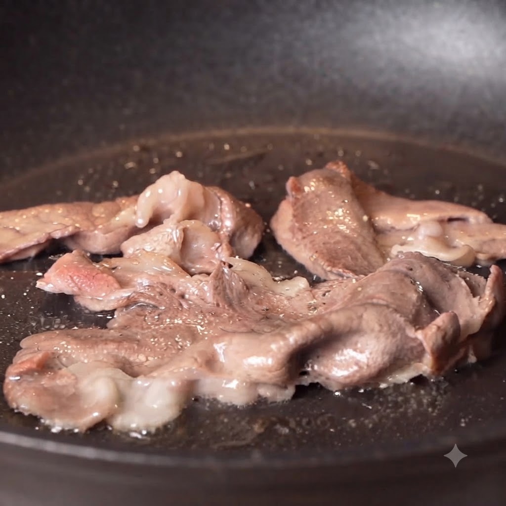 Black pepper and salt being sprinkled onto seared beef slices cooking in a pan.