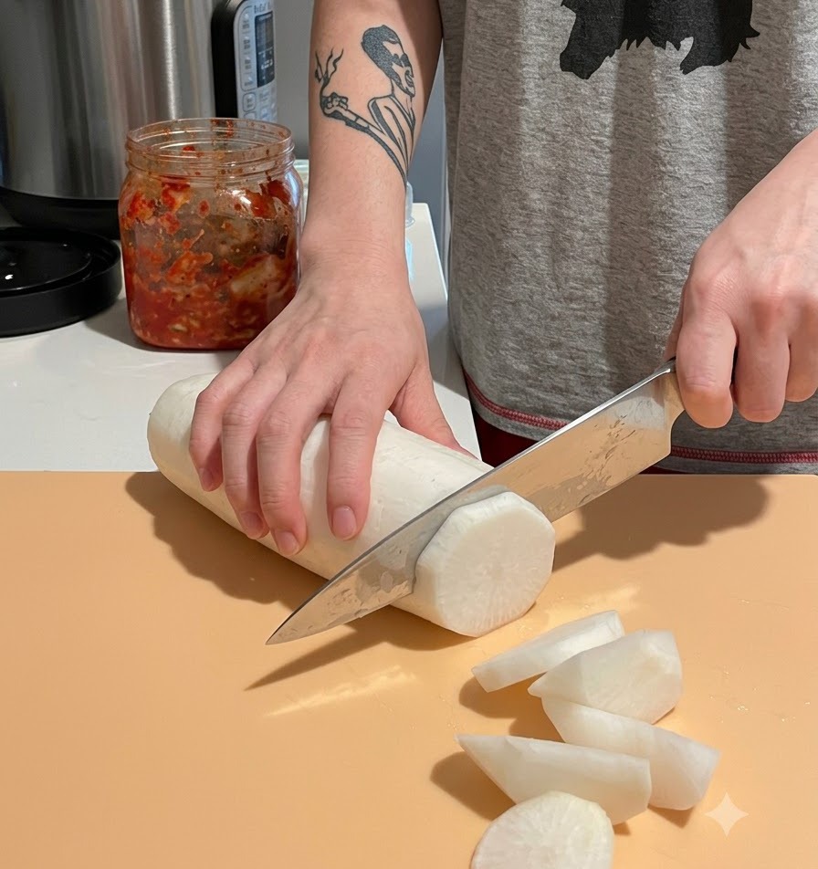 Slicing a peeled white daikon radish into large, thick chunks on a cutting board.