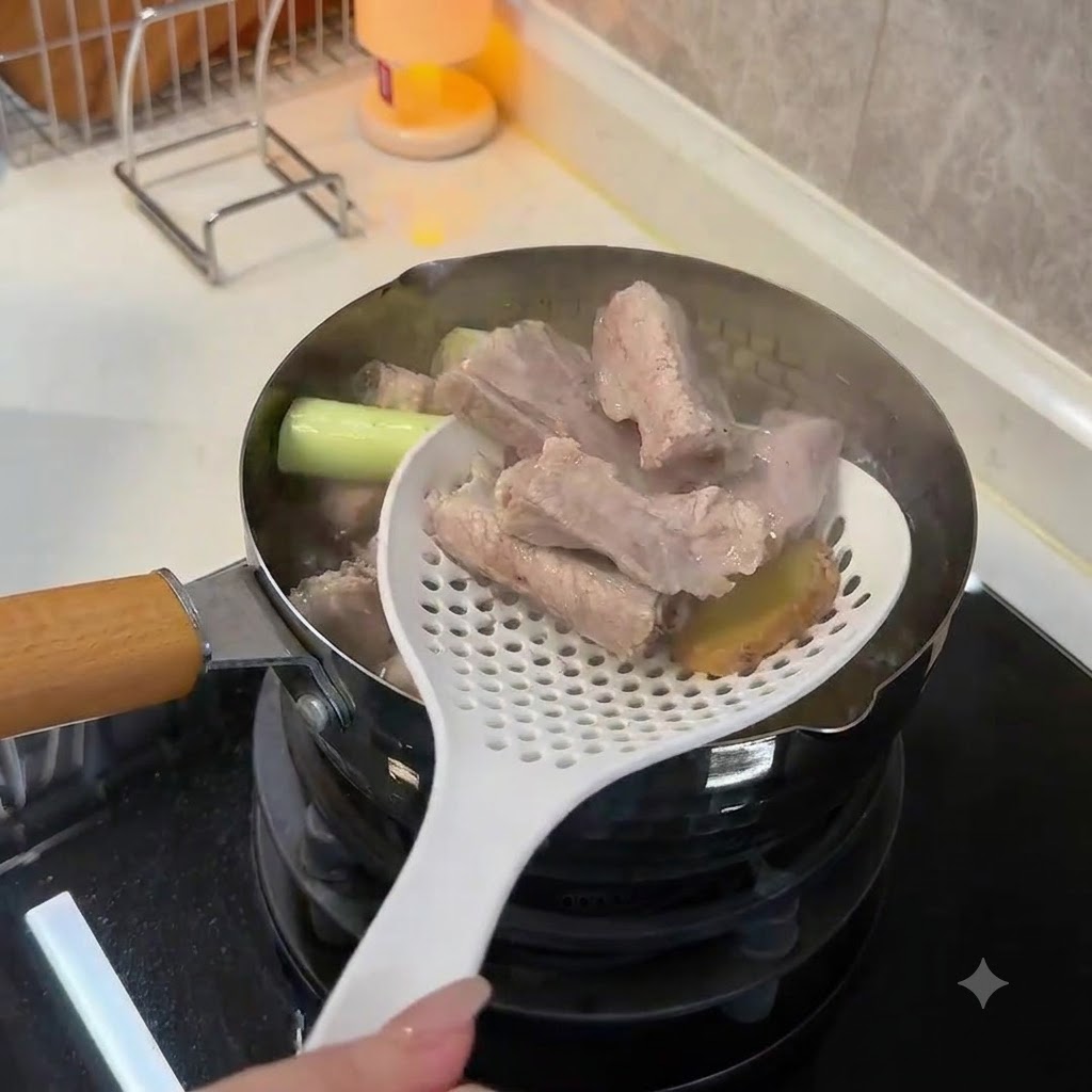 Using a white slotted spoon to lift blanched, opaque pork ribs and ginger slices out of boiling water.