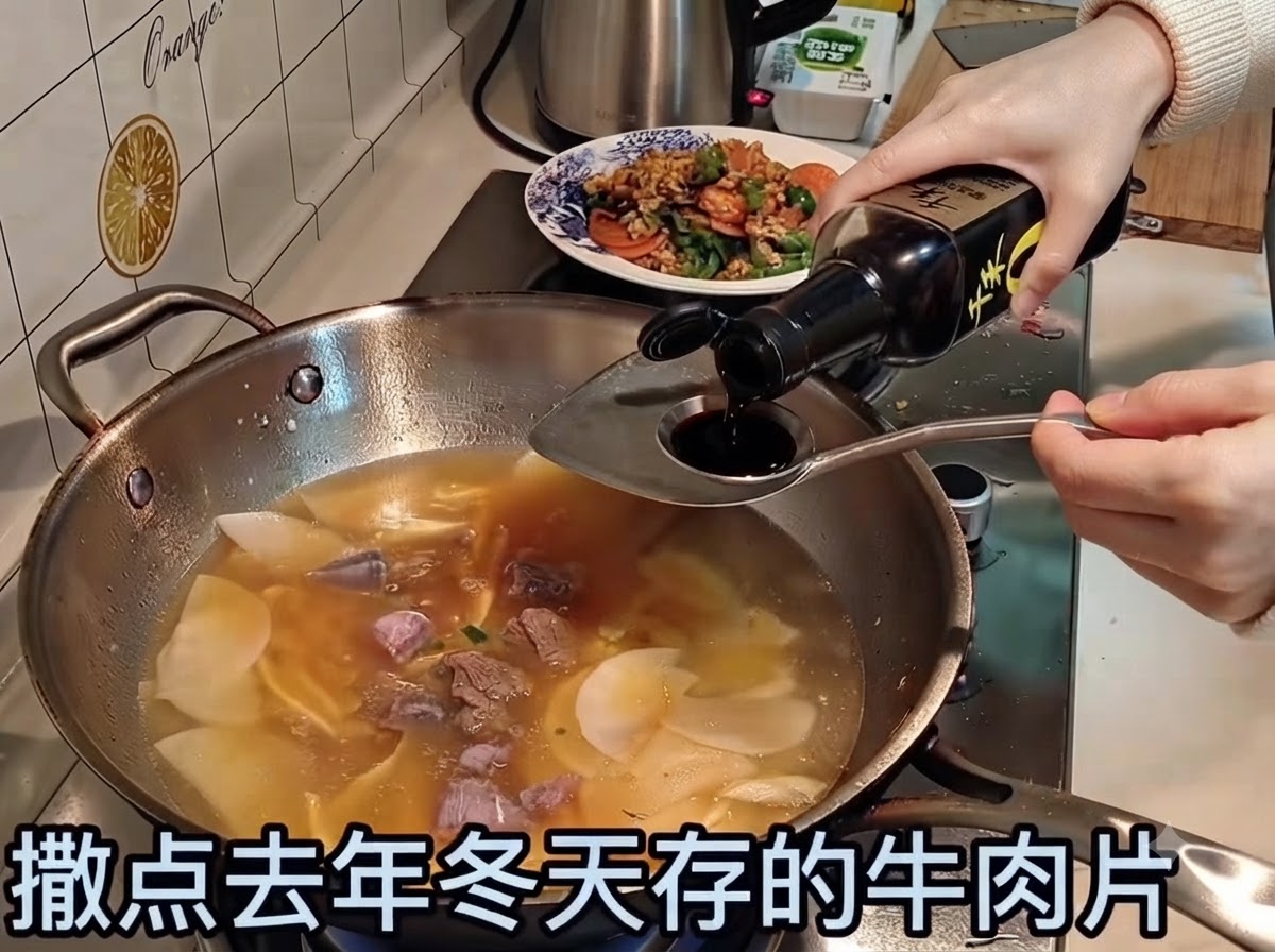 Soy sauce being poured into a simmering broth containing beef slices and vegetables.