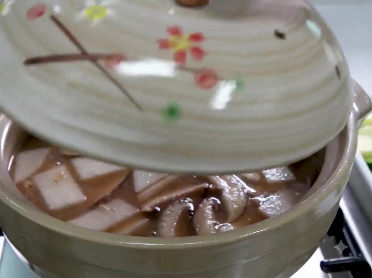 A hand placing a lid on a ceramic pot filled with broth, sliced radish, and shiitake mushrooms.
