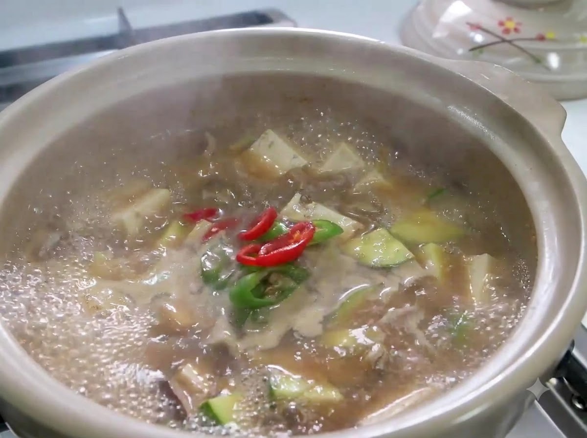 Sliced red and green chili peppers and green onions simmering in a bubbling pot of Doenjang Jjigae.