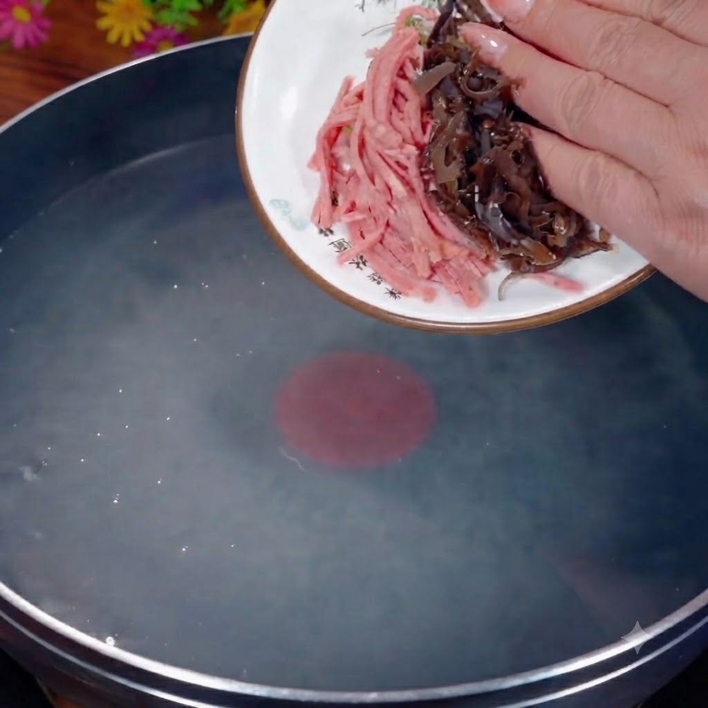 Shredded black fungus and ham being poured from a white plate into a pot of boiling water.