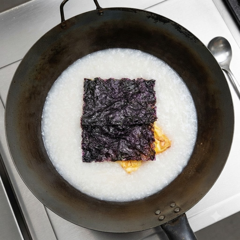 Dried seaweed floating on top of the white soup in the wok.
