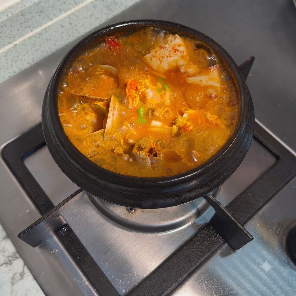 Finished Korean spicy soft tofu stew garnished with chopped green onions in a hot stone pot.