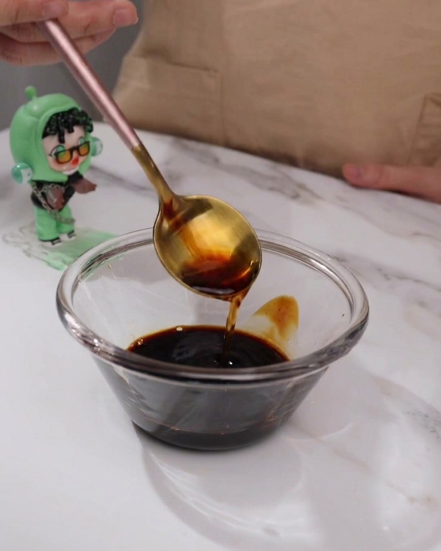 Teriyaki sauce ingredients being mixed in a small glass bowl with a spoon.