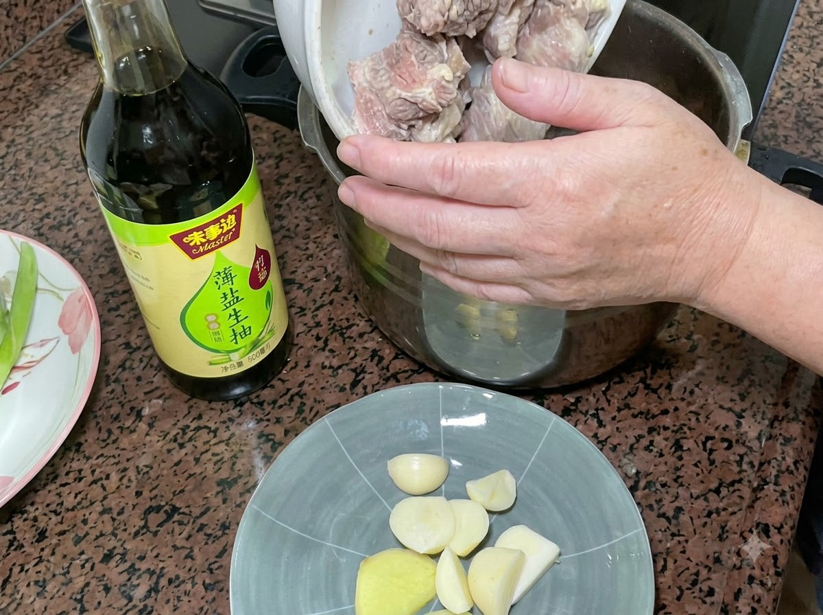 Blanched pork ribs being poured into a pressure cooker next to a bottle of light soy sauce and a plate of garlic and ginger.