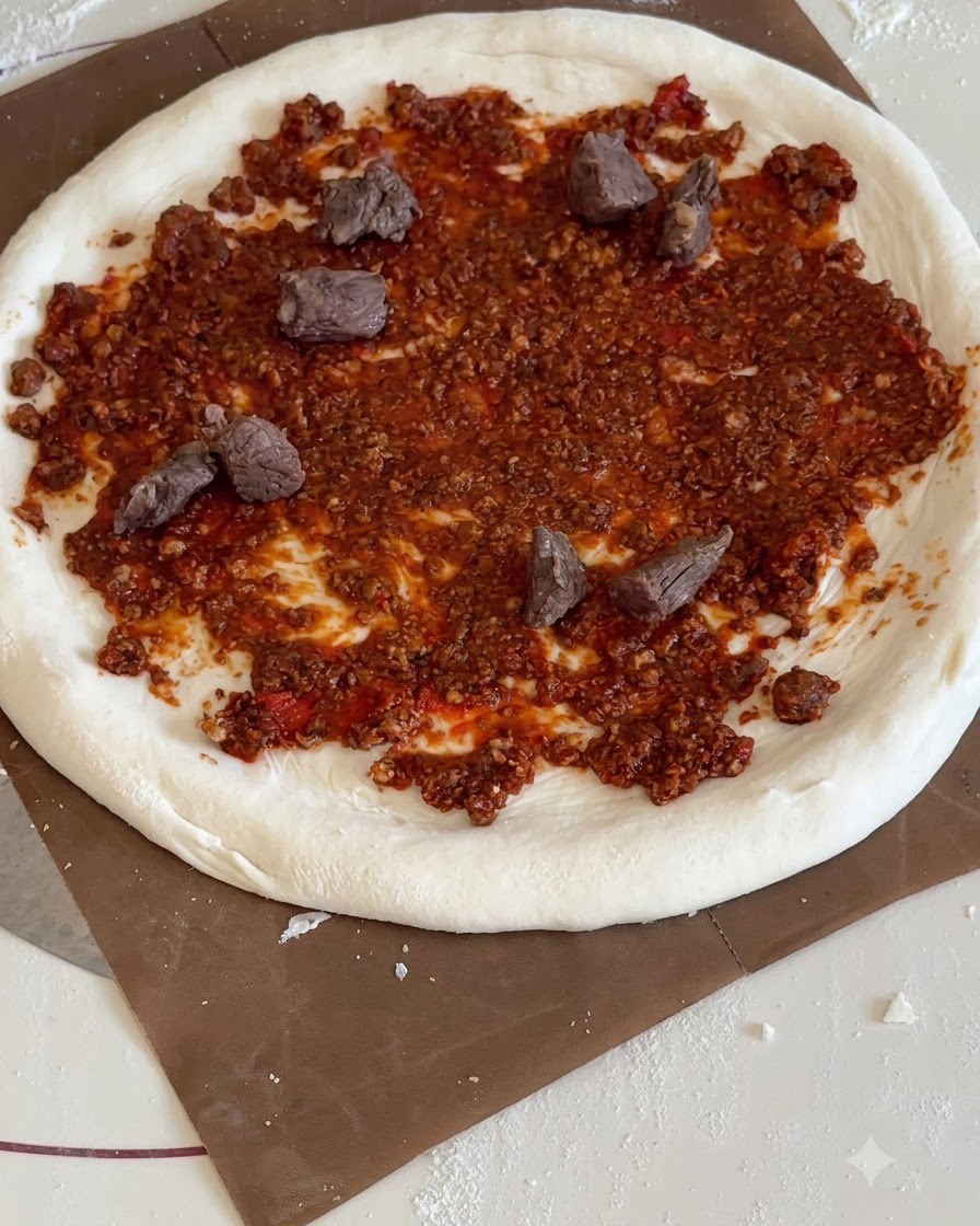 Triangular chunks of yellow pineapple and cooked beef pieces distributed across the red sauce pizza base.