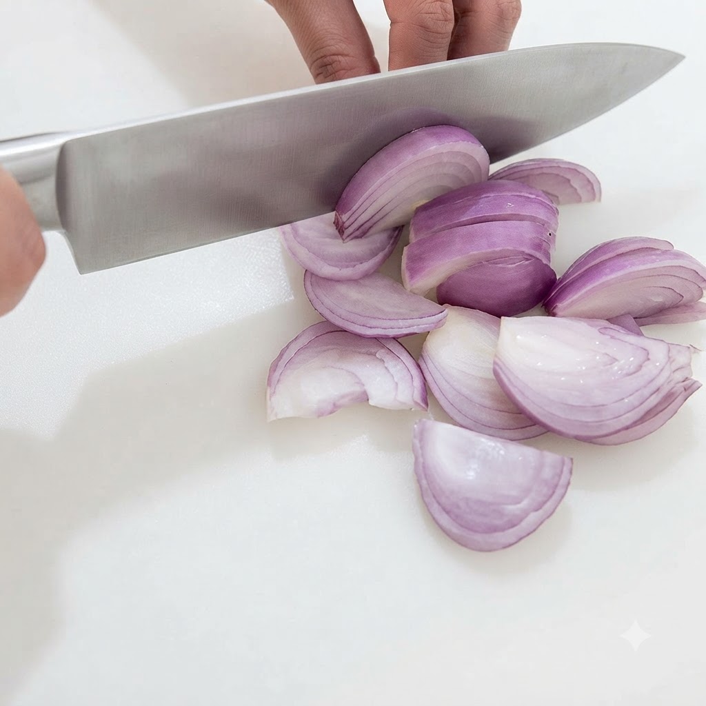 Hands using a chefs knife to expertly slice and dice a halved red onion into small pieces on a clean white cutting board.