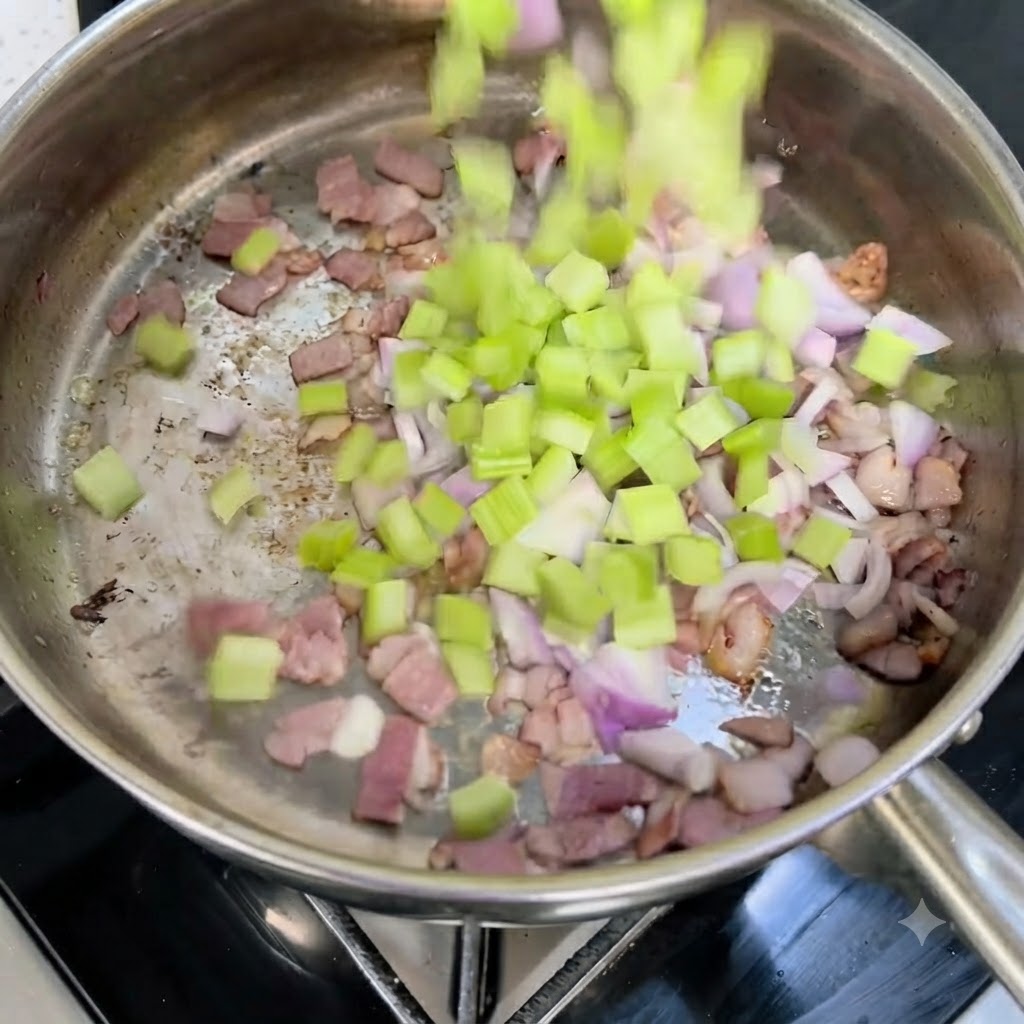 Diced celery and red onions falling into a hot pan with crispy bacon pieces.