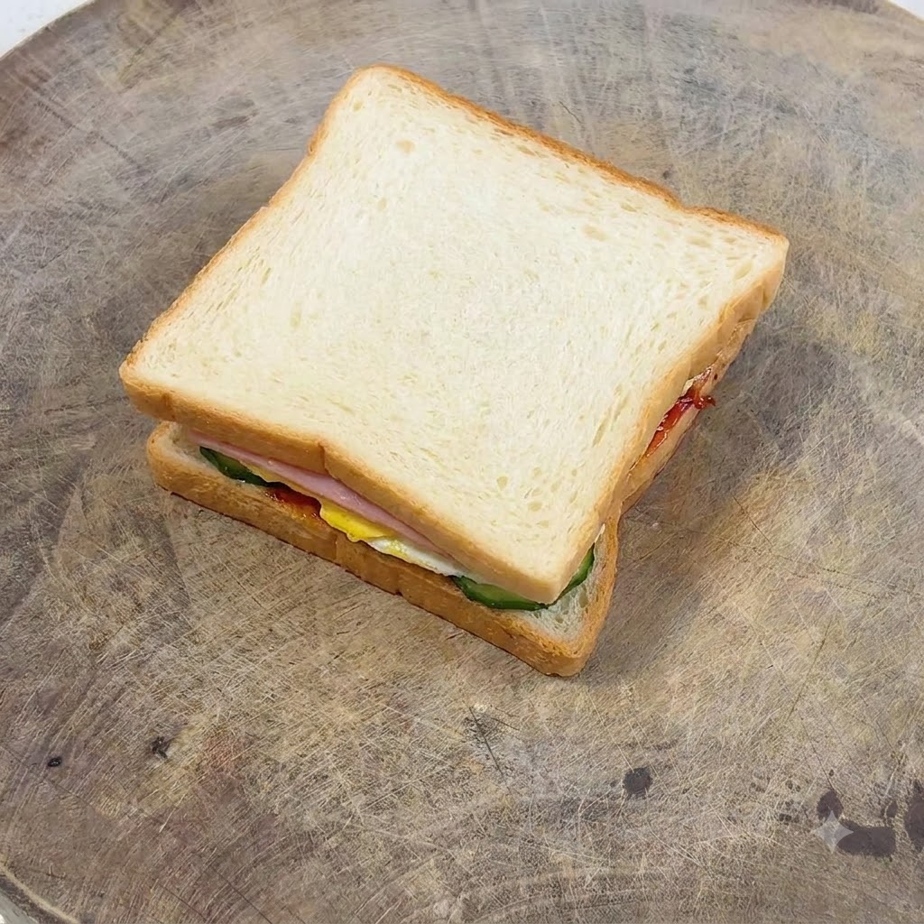 A fork spreading mayonnaise smoothly over a golden-brown slice of toasted bread.