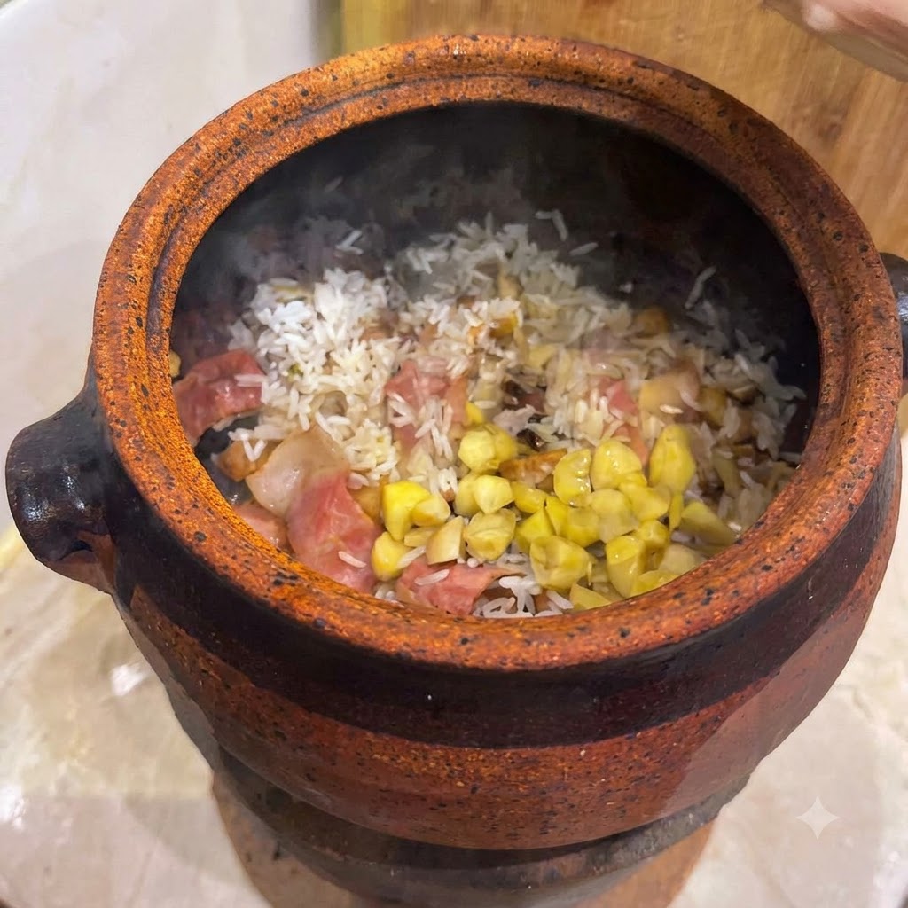 Ginkgo nuts and yellow chestnut pieces scattered on top of a mixed rice and bacon base inside a clay pot.