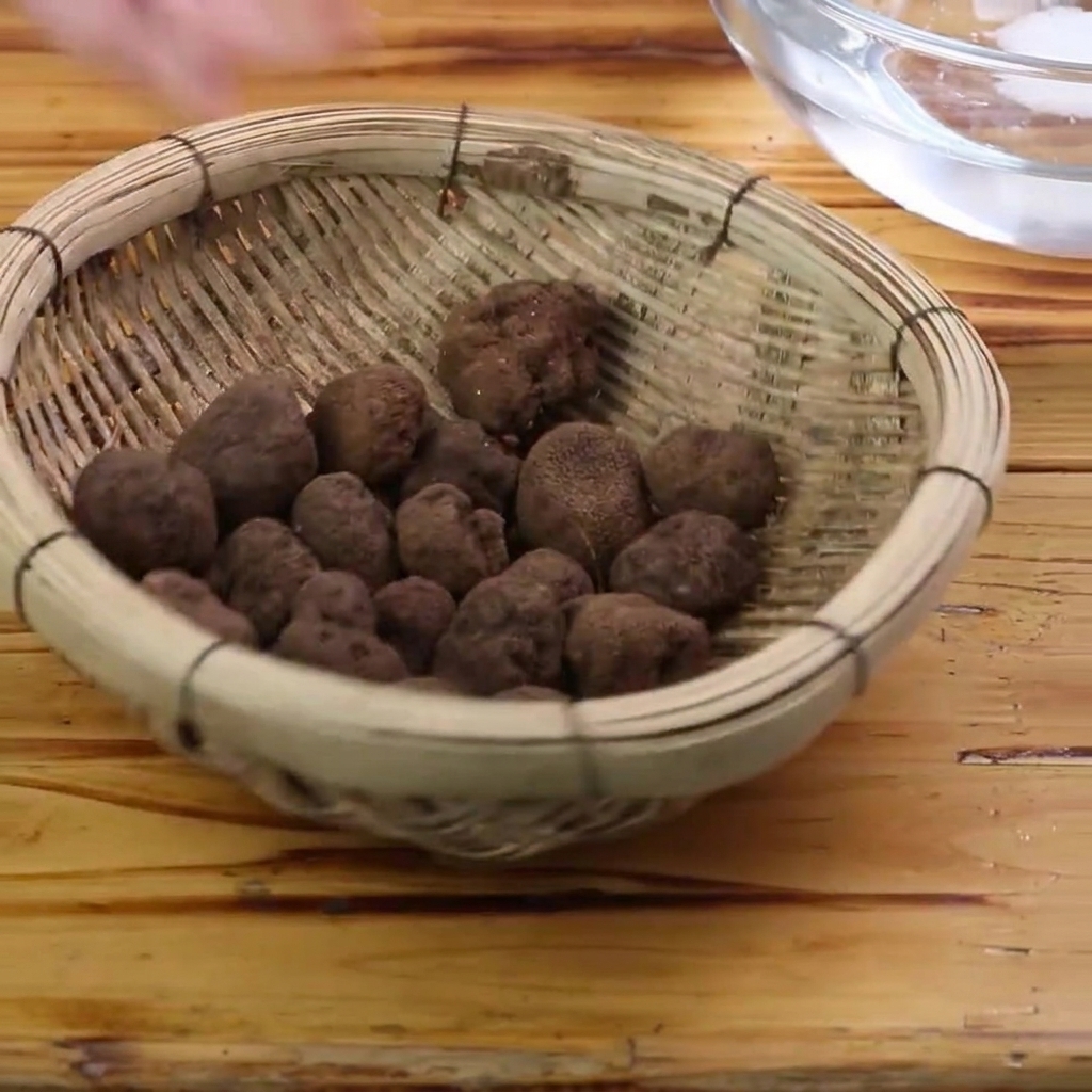 Fresh black truffles being scrubbed clean with a brush inside a bowl of water.