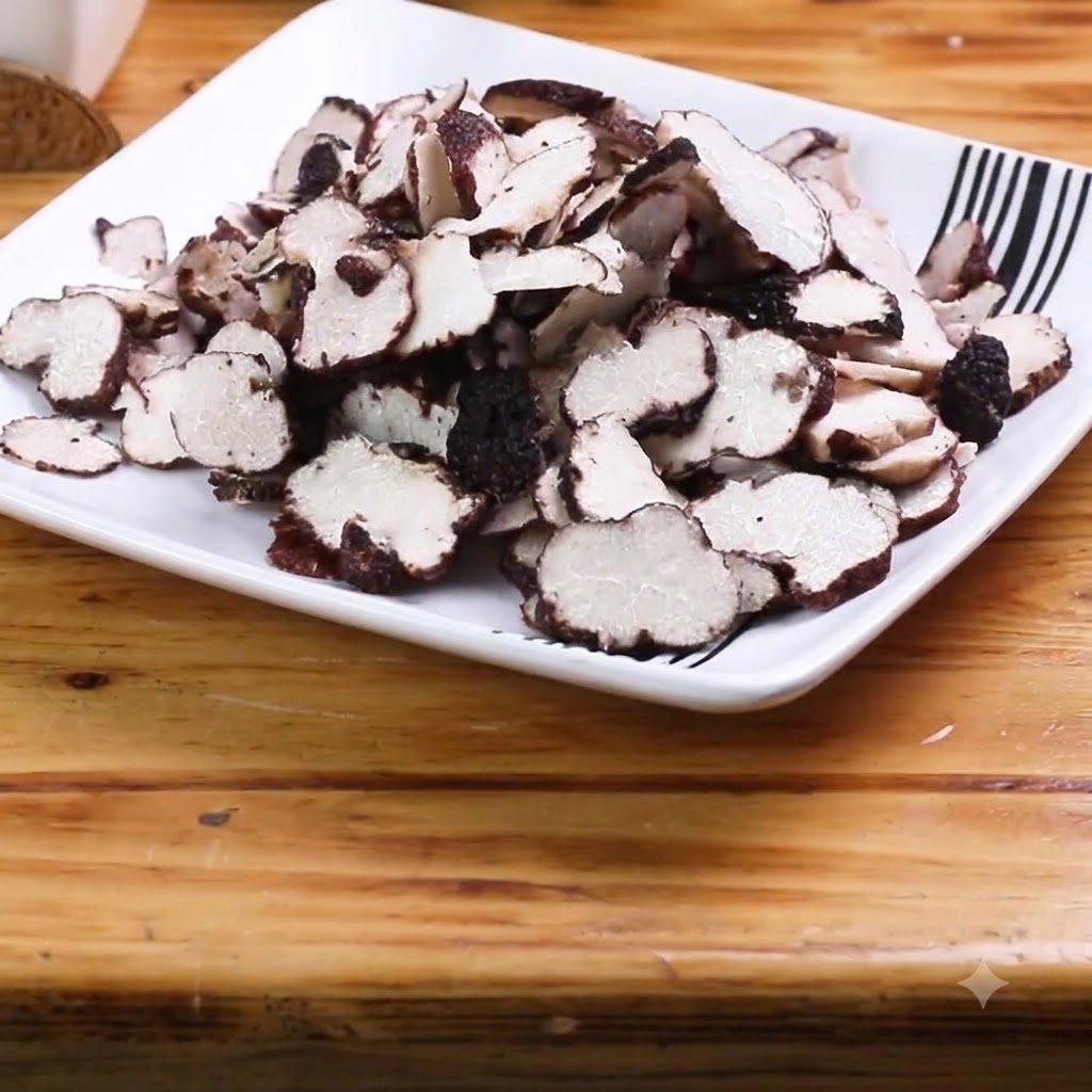 Thinly sliced garlic cloves arranged on a wooden cutting board.