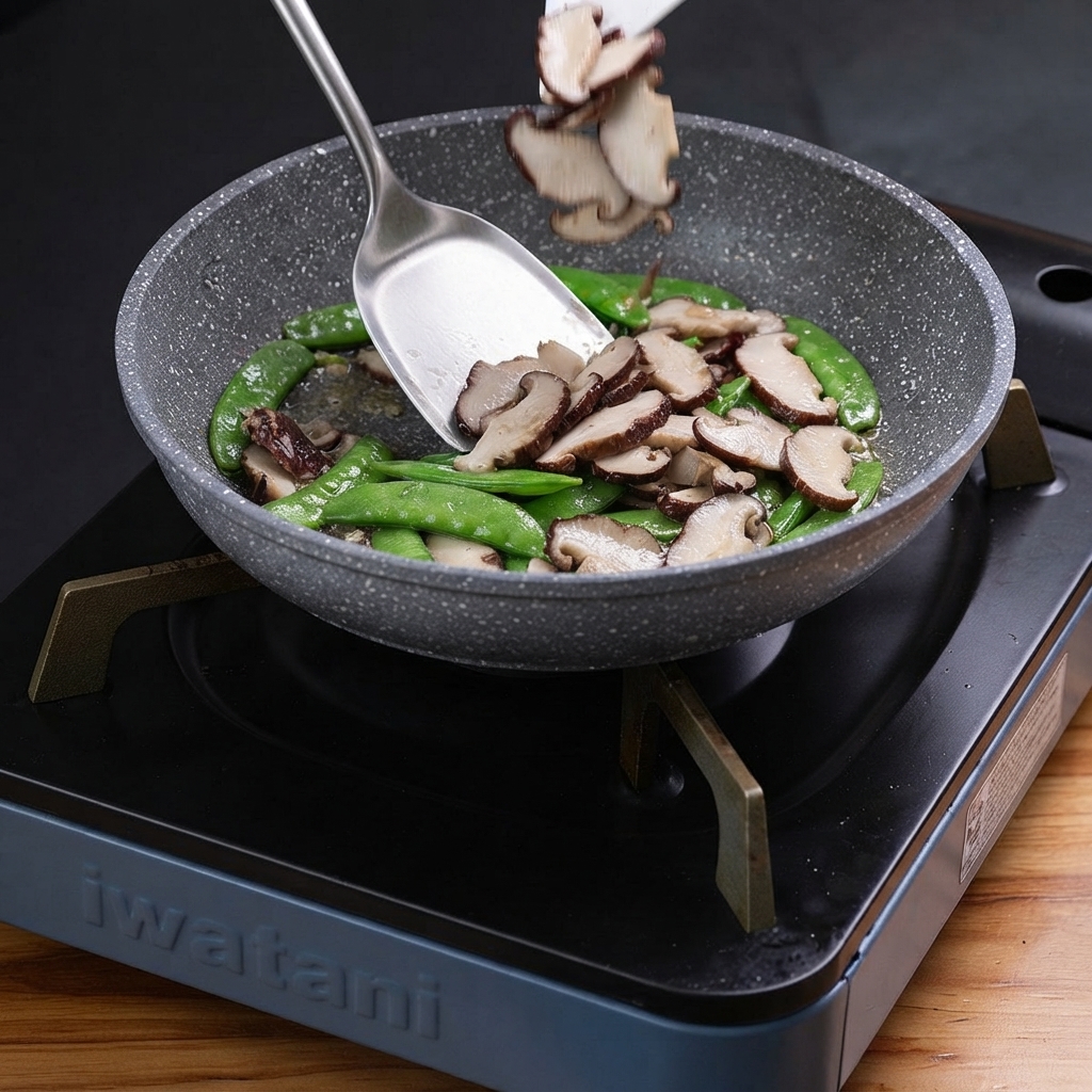 Sliced truffles being tossed into a pan containing sautéed green peppers and garlic.