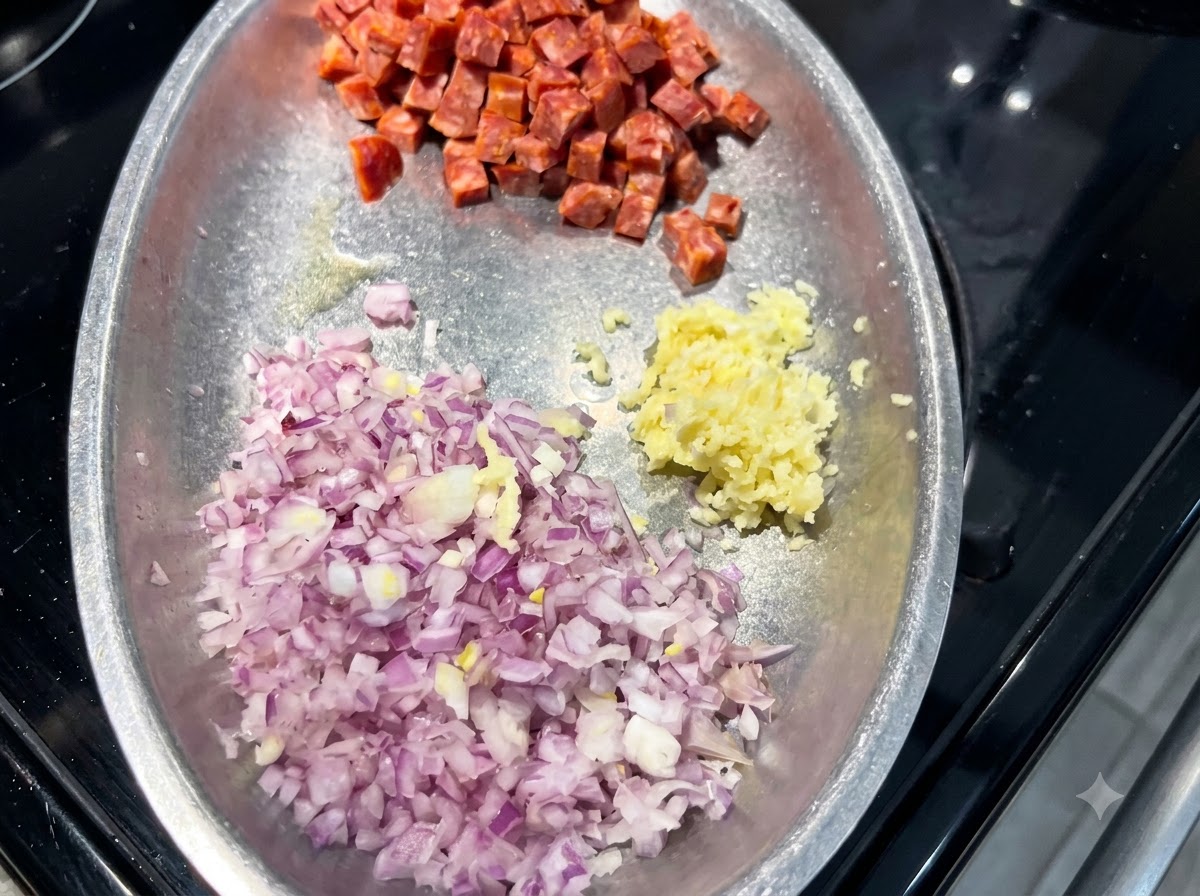 A metal plate containing mounds of diced red onion, minced garlic, and cubed Spanish chorizo.