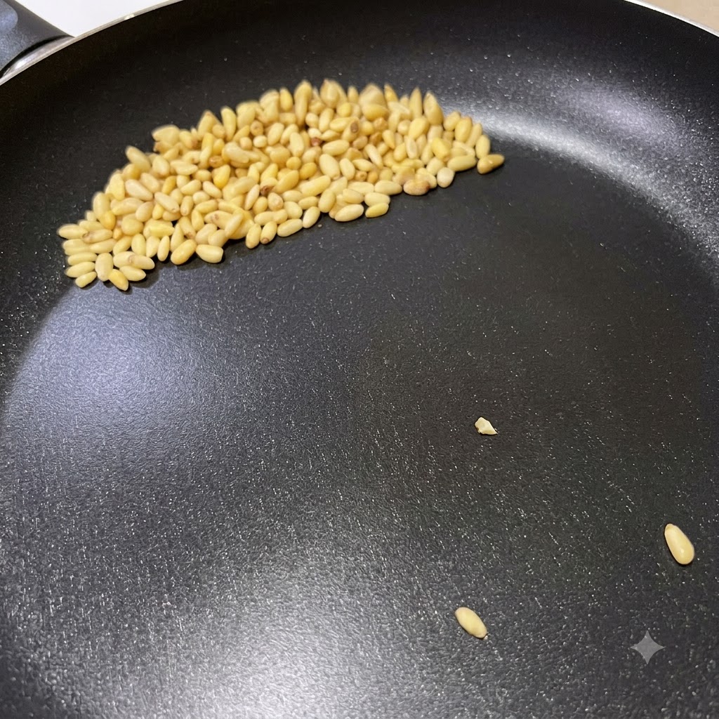 Pine nuts browning in a dry frying pan during the preparation for Italian pesto pasta.