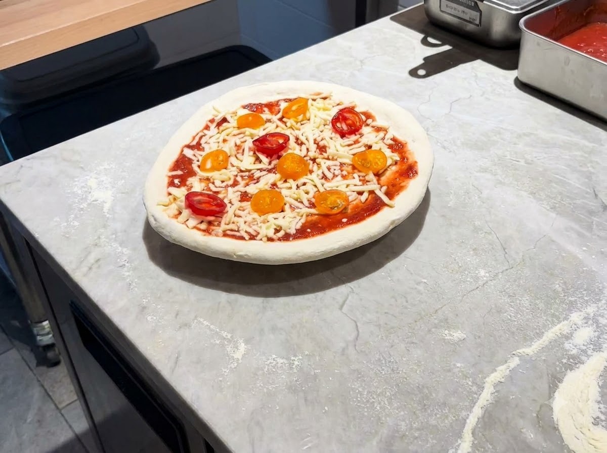 A fully assembled pizza resting on a metal peel on a marble countertop.