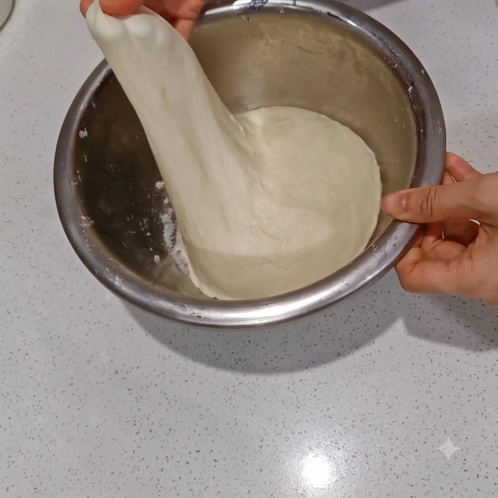 Stretching the water-infused dough to show a thin, translucent membrane layer.