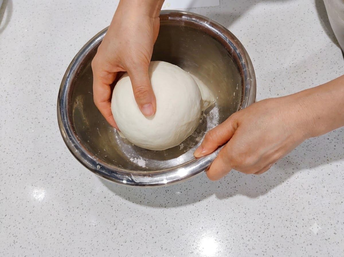 Two shaped dough portions resting side-by-side inside a clear rectangular proofing container.